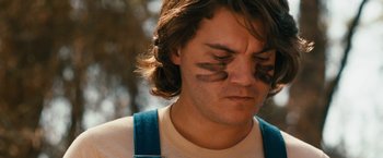 Movie still from “Prince Avalanche” (2013), directed by David Gordon Green – A young man with long brown hair wearing a white shirt; Close Up shot, Low angle