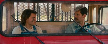Movie still from “Prince Avalanche” (2013), directed by David Gordon Green – Two men are sitting in the back of a red bus; Medium shot, Over the shoulder angle