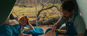 Movie still from “Prince Avalanche” (2013), directed by David Gordon Green – A man and a woman sitting on the ground near a tree; Medium shot, Over the shoulder angle