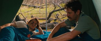 Movie still from “Prince Avalanche” (2013), directed by David Gordon Green – A man and a woman sitting on a blanket in the woods; Medium shot, Over the shoulder angle