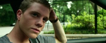 Movie still from “Project Almanac” (2015), directed by Dean Israelite – A person sitting in a car with trees in the background; Close Up shot, Over the shoulder angle