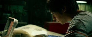 Movie still from “Project Almanac” (2015), directed by Dean Israelite – A person reading a book in a dark room; Close Up shot, High angle