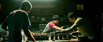 Movie still from “Project Almanac” (2015), directed by Dean Israelite – A group of people working in a room; Medium shot, Low angle