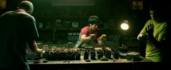 Movie still from “Project Almanac” (2015), directed by Dean Israelite – A man working in a shop on electronics; Medium shot, Low angle