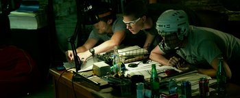 Movie still from “Project Almanac” (2015), directed by Dean Israelite – Two men are working on a computer on a table; Medium shot, Low angle