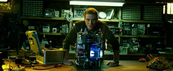 Movie still from “Project Almanac” (2015), directed by Dean Israelite – A man is posing for a picture with a computer; Medium shot, Low angle