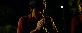 Movie still from “Project Almanac” (2015), directed by Dean Israelite – A young man is praying in the dark; Close Up shot, Low angle