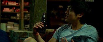 Movie still from “Project Almanac” (2015), directed by Dean Israelite – A man holding a bottle of beer in his hand; Medium shot, Over the shoulder angle