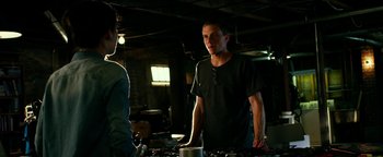 Movie still from “Project Almanac” (2015), directed by Dean Israelite – A man standing next to another man in a room; Medium shot, Over the shoulder angle
