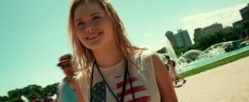 Movie still from “Project Almanac” (2015), directed by Dean Israelite – A woman with blonde long hair and a flag shirt; Close Up shot, Over the shoulder angle