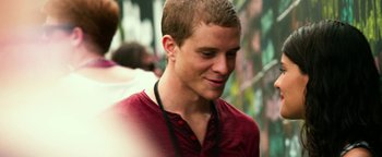 Movie still from “Project Almanac” (2015), directed by Dean Israelite – A young man in a red shirt is smiling; Close Up shot, Over the shoulder angle