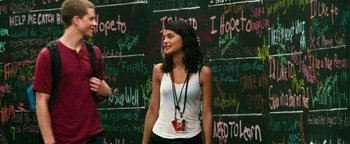 Movie still from “Project Almanac” (2015), directed by Dean Israelite – A woman standing in front of a chalkboard wall; Medium shot, Over the shoulder angle