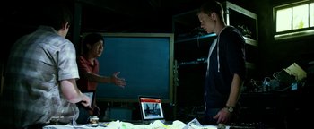 Movie still from “Project Almanac” (2015), directed by Dean Israelite – Two people standing in front of an open laptop computer; Medium shot, Over the shoulder angle