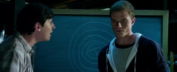 Movie still from “Project Almanac” (2015), directed by Dean Israelite – Two men standing next to each other in front of a chalkboard; Medium shot, Over the shoulder angle