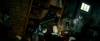 Movie still from “Project Almanac” (2015), directed by Dean Israelite – A woman sitting in front of a mirror in a room filled with bookshelves; Wide shot, High angle
