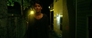 Movie still from “Project Almanac” (2015), directed by Dean Israelite – A woman standing in front of a building at night; Medium shot, Low angle