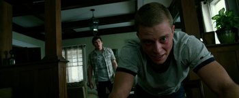 Movie still from “Project Almanac” (2015), directed by Dean Israelite – Two young men in a living room , one of whom is looking at the camera; Medium shot, Low angle