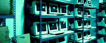 Movie still from “Project Almanac” (2015), directed by Dean Israelite – A row of computer monitors sitting on top of a shelf; Extreme Wide shot, High angle