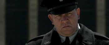 Movie still from “Public Enemies” (2009), directed by Michael Mann – A person wearing a uniform; Close Up shot, Over the shoulder angle