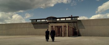 Movie still from “Public Enemies” (2009), directed by Michael Mann – Two men are standing in front of an old jail; Extreme Wide shot, Low angle