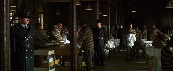 Movie still from “Public Enemies” (2009), directed by Michael Mann – A group of men standing next to each other in a room; Wide shot, High angle