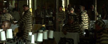 Movie still from “Public Enemies” (2009), directed by Michael Mann – A group of men in striped uniforms working in a room; Wide shot, High angle