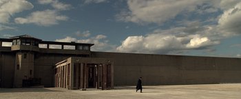 Movie still from “Public Enemies” (2009), directed by Michael Mann – A man walking in front of a building; Extreme Wide shot, Low angle