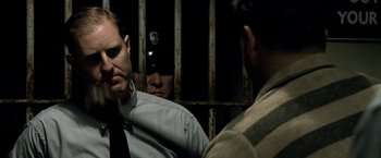 Movie still from “Public Enemies” (2009), directed by Michael Mann – A man in a jail cell with another man in a prison cell; Close Up shot, Over the shoulder angle