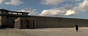 Movie still from “Public Enemies” (2009), directed by Michael Mann – An empty parking lot next to a building with clouds in the background; Extreme Wide shot, Low angle