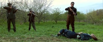 Movie still from “Public Enemies” (2009), directed by Michael Mann – A group of men standing in the grass with guns; Wide shot, Low angle