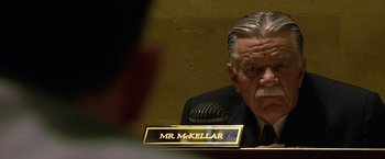 Movie still from “Public Enemies” (2009), directed by Michael Mann – An older man sitting in front of a microphone in a room; Close Up shot, Low angle