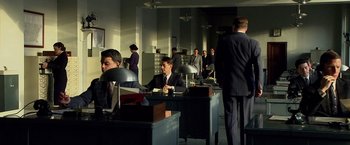Movie still from “Public Enemies” (2009), directed by Michael Mann – A group of men in suits and ties sitting at desks; Wide shot, High angle