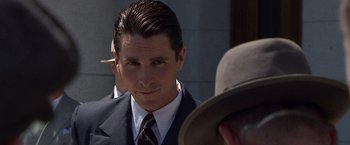 Movie still from “Public Enemies” (2009), directed by Michael Mann – A person wearing a suit and tie; Close Up shot, Over the shoulder angle
