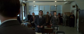 Movie still from “Public Enemies” (2009), directed by Michael Mann – A group of men in suits standing in a room; Wide shot, Low angle