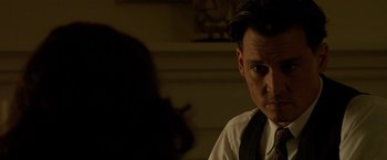 Movie still from “Public Enemies” (2009), directed by Michael Mann – A man in a white dress shirt and tie; Close Up shot, Over the shoulder angle