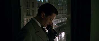 Movie still from “Public Enemies” (2009), directed by Michael Mann – A man talking on a cell phone while standing in front of a window; Close Up shot, Low angle