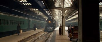 Movie still from “Public Enemies” (2009), directed by Michael Mann – A train is on the tracks at a train station; Extreme Wide shot, High angle