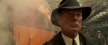 Movie still from “Public Enemies” (2009), directed by Michael Mann – A man wearing a hat and a black suit; Close Up shot, Low angle