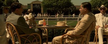 Movie still from “Public Enemies” (2009), directed by Michael Mann – A couple of people sitting at a table with hats on it; Medium shot, High angle