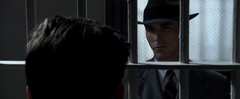 Movie still from “Public Enemies” (2009), directed by Michael Mann – A man in a suit and a hat looking at another man in a suit and a hat; Close Up shot, Over the shoulder angle