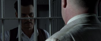 Movie still from “Public Enemies” (2009), directed by Michael Mann – A man looking at himself in the mirror in a jail cell; Close Up shot, Over the shoulder angle