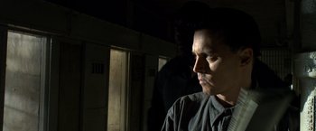 Movie still from “Public Enemies” (2009), directed by Michael Mann – A man standing next to another man in a dark room; Close Up shot, Low angle