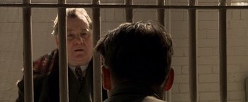 Movie still from “Public Enemies” (2009), directed by Michael Mann – A man in a suit and tie standing next to another man in a suit and tie; Close Up shot, Over the shoulder angle