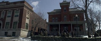 Movie still from “Public Enemies” (2009), directed by Michael Mann – A group of men standing next to a brick wall; Extreme Wide shot, Low angle