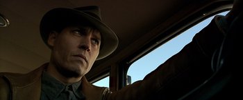Movie still from “Public Enemies” (2009), directed by Michael Mann – A man wearing a hat looking out of a car window; Close Up shot, Low angle
