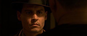 Movie still from “Public Enemies” (2009), directed by Michael Mann – A person wearing a hat; Close Up shot, Over the shoulder angle