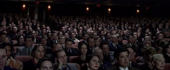 Movie still from “Public Enemies” (2009), directed by Michael Mann – A group of people sitting in a theater; Wide shot, High angle