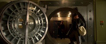 Movie still from “Public Enemies” (2009), directed by Michael Mann – A man standing in front of an open bank vault door; Wide shot, Low angle