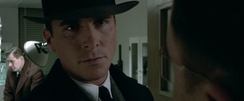 Movie still from “Public Enemies” (2009), directed by Michael Mann – A man wearing a hat and a tie; Close Up shot, Over the shoulder angle