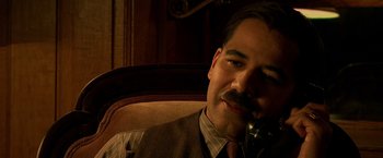 Movie still from “Public Enemies” (2009), directed by Michael Mann – A man sitting in a chair talking on a phone; Close Up shot, High angle